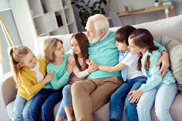 Photo of happy lovely charming big family enjoying spend time together grandfather in glasses hug embrace children at home house
