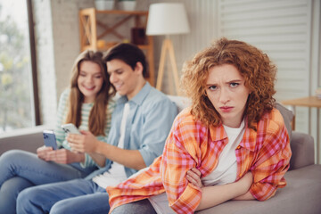 Three young friends relaxing in a bright living room with phones during a casual indoor gathering on a sunny day
