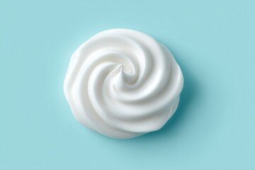 Top view of smooth swirl of white moisturizing cream with glossy texture on pastel blue background, skincare cosmetic product design