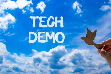 Tech demo symbol. Concept word Tech demo on beautiful blue sky. Businessman's hand with wooden...