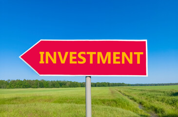 Investment symbol. Concept word Investment on beautiful red road sign. Beautiful blue sky green grass and forest peaceful nature background. Business investment concept. Copy space.