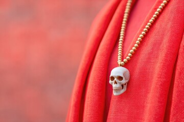 Fototapeta premium Intricate skull pendant hangs from chain, contrasting vibrant re