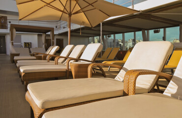 Pooldeck or swimmingpool with sun deck on modern cruiseship or cruise ship liner with elegant lounge furniture deck chairs and rattan sun beds loungers