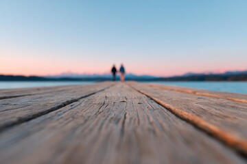 Wooden dock stretches into serene waters, with silhouettes of tw