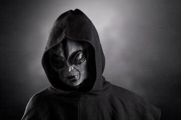 Mysterious humanoid alien at night over dark misty background