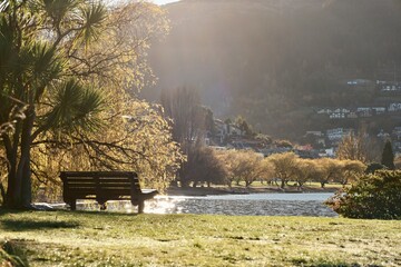 May 2025: A person on a bench in Queenstown Gardens, overlooking Lake Wakatipu on a sunny autumn...