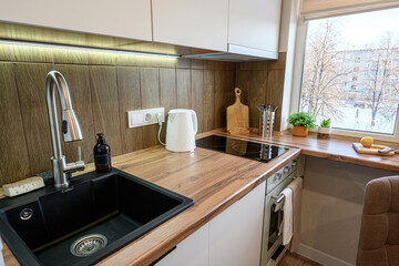 cozy kitchen corner with wood countertops, a black sink, and a window view. Natural light fills the space