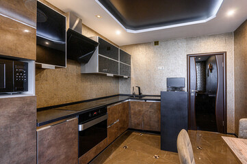 stylish kitchen featuring dark countertops, brown cabinetry, and a mix of glossy and matte...
