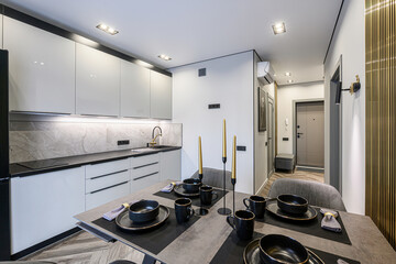 modern kitchen and dining area. Grey cabinets, marble backsplash, black hardware, and a set table...