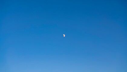 Pale crescent moon in a clear blue sky