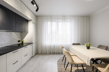 bright, modern kitchen and dining area with white cabinets, a black countertop, and a dining table...