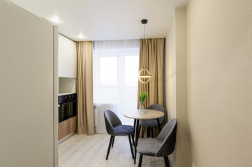 Cozy, modern kitchen/dining area with round table, three chairs, and natural light