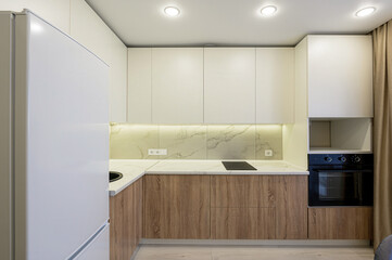 modern kitchen featuring white upper cabinets, wood-grain lower cabinets, and a marble-patterned...