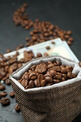 Roasted coffee beans in sack on dark textured table, closeup