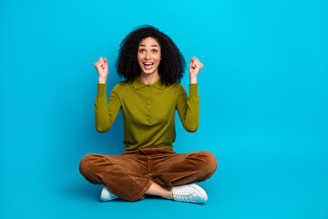 Cheerful young woman in casual attire with a vibrant blue background expressing happiness and...