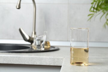 Sample of dirty water in beaker near sink indoors