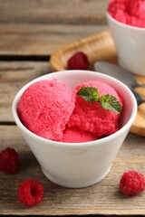 Delicious raspberry sorbet with mint in bowl and fresh berries on wooden table, closeup