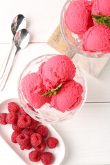 Delicious raspberry sorbet with mint in dessert bowls, spoons and fresh berries on white wooden...