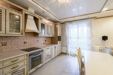 bright kitchen with beige cabinets, tile backsplash, and a formal dining area. Elegant design elements throughout