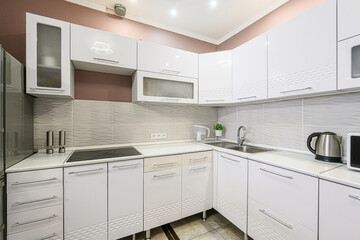 modern kitchen with white cabinets, stainless steel appliances, and textured backsplash. The design...
