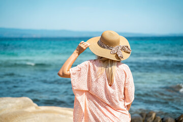 Waves, relax and back of woman at beach for summer adventure, peace and travel on holiday. Sun hat and female person with sunshine by ocean for tropical, island vacation and tourism 