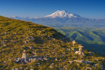 panoramic view of the Bolshoy Bermamyt plateau with stone turrets built on a grassy slope, with the...