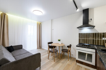 Cozy studio apartment with a sofa, dining table, and compact kitchen. Neutral tones create a clean...