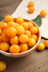 Ripe yellow cherry plums and leaves on wooden table, closeup
