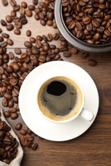 Aromatic coffee in cup and beans on wooden table, flat lay