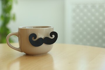 Happy Father's Day. Cup with mustache on wooden table indoors, closeup. Space for text