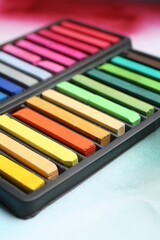 Naklejka premium Colorful chalk pastels in trays on color background, closeup