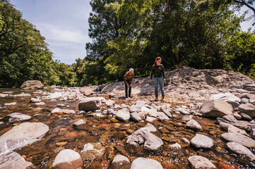 Mother and daughter observing small details like plants, stones, insects, and having a good time by...