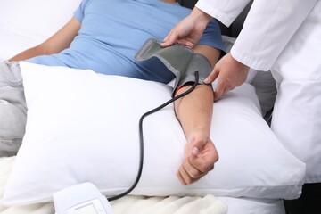 Doctor checking man's heart rate and blood pressure via sphygmomanometer at home, closeup