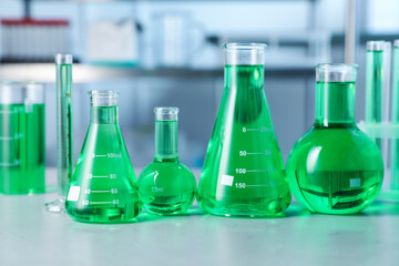 Different laboratory glassware with green liquid on light table indoors