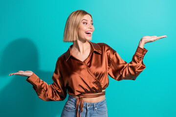 Young stylish woman showcasing gestures while standing against turquoise background in casual outfit