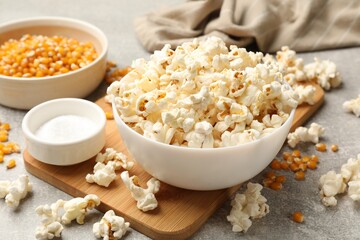 Tasty popcorn and corn kernels on light grey table, closeup