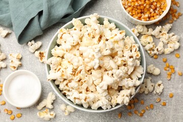 Tasty popcorn and corn kernels on light grey table, flat lay