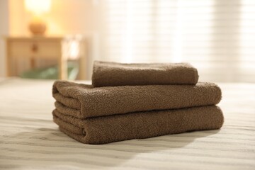 Stack of clean towels on bed linens at home, closeup