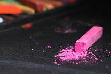 Pink chalk pastel on black table, closeup
