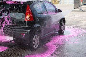Washing auto with high pressure water jet at car wash, closeup