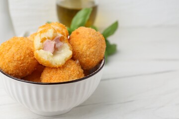 Delicious fried croquette balls in bowl on white wooden table, closeup. Space for text