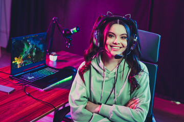 Young female gamer streaming with a headset in a cozy neon-lit gaming setup