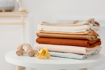 Stack of clean baby clothes and accessories on white table indoors, closeup