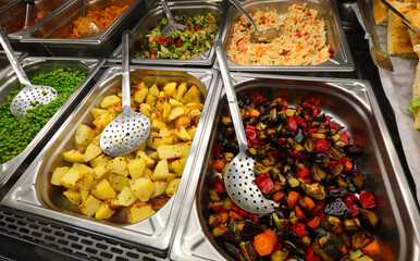 hot eggplants and baked potatoes and other vegetables and hot dishes in a restaurant canteen