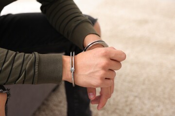 Man in metal handcuffs on blurred background, closeup. Space for text