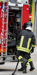 firefighters with uniforms and protective helmets and fire truck in action during emergency