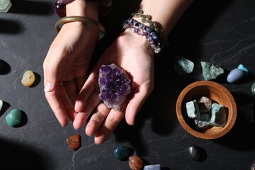 Woman with healing stones at black table, closeup