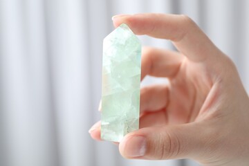 Woman with healing crystal on blurred background, closeup