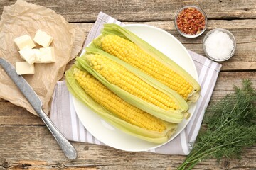 Tasty boiled corncobs, dill and spices on wooden table, flat lay