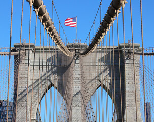 Obraz premium New York city with Large American Flag on the top of Tower of Brooklyn Bridge and steel cables